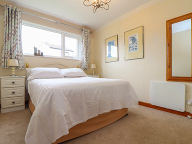 A bedroom with a double bed bedside tables lamps framed pictures and a wall mirror at Skylarks Trevellas Nr St Agnes