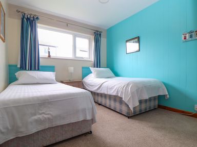 A bedroom with two single beds a nightstand and window at Skylarks Trevellas Nr St Agnes