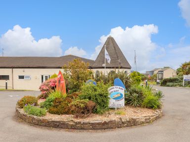 A roundabout with plants and surfboards in front of a building with a cone-shaped roof at Skylarks Trevellas Nr St Agnes