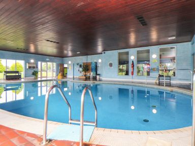 An indoor swimming pool with metal handrails and blue walls at Skylarks Trevellas Nr St Agnes