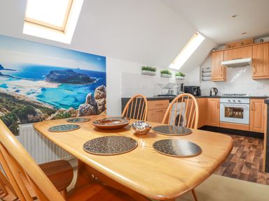 A kitchen and dining area with wooden cabinets and table with chairs at 20 Keay Heights in St Austell