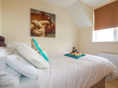 A bedroom with a bed pillows and a small stuffed animal near a window at 20 Keay Heights in St Austell