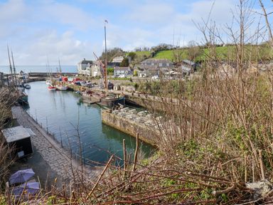 A harbor with boats docked along stone piers and buildings on the waterfront at 20 Keay Heights in St Austell