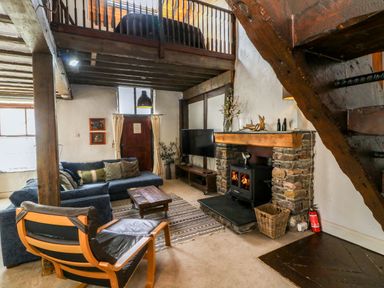 A living room with wooden beams a fireplace and seating at The Old Smithy in Lynton