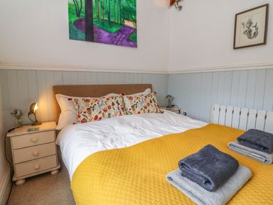 A bedroom with a bed with yellow blanket and patterned pillows at The Old Smithy in Lynton