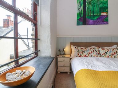 A bedroom with a bed pillow and nightstand next to a window with a bowl of stones at The Old Smithy in Lynton