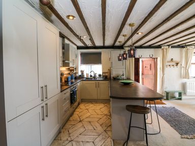 A kitchen with cabinets a countertop and stools at The Old Smithy in Lynton