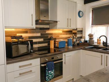 A kitchen with a microwave oven stove kettle and sink at The Old Smithy in Lynton