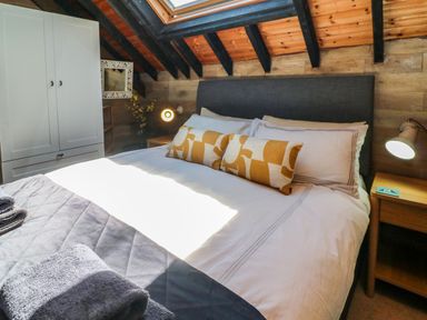 A bedroom with a bed under a skylight and a wardrobe at The Old Smithy in Lynton