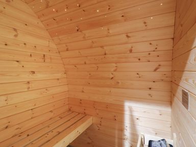 An interior wood paneled sauna room with a wooden bench and a heater
