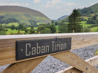 A sign labeled Caban Tirion with mountains and greenery in the background at Caban Tirion in Dinas Mawddwy near Dolgellau