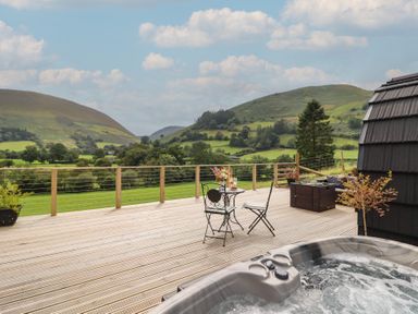 A deck with a hot tub and seating area at Caban Tirion near Dinas Mawddwy