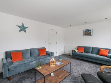A living room with two blue sofas and orange cushions a wooden coffee table and a wall star at Dotties Retreat in Weymouth