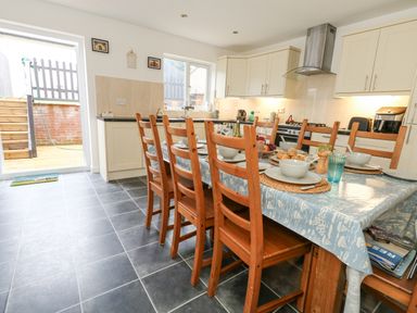 A kitchen with a dining table set for a meal and wooden chairs at Dotties Retreat in Weymouth