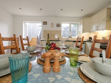 A kitchen with a dining table set with bowls glasses plates and bread at Dotties Retreat in Weymouth