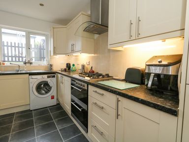 A kitchen with appliances and cabinets under a window at Dotties Retreat in Weymouth