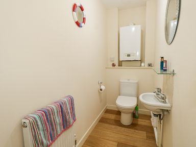 A small bathroom with a toilet sink and a radiator with a striped towel at Dotties Retreat in Weymouth