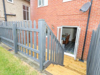 A wooden fenced outdoor area with stairs leading to a tiled indoor dining room at Dotties Retreat in Weymouth