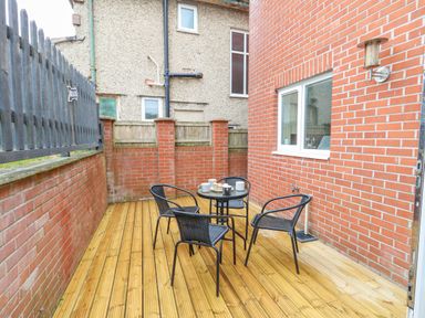 A small outdoor patio area with a round table and four chairs on wooden decking at Dotties Retreat in Weymouth