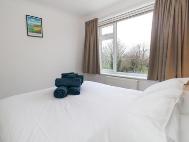 A bedroom with a bed and folded towels on it by a window with brown curtains at The Swanage Rail Lookout in Swanage