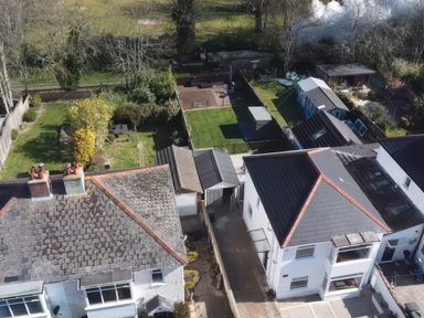 An aerial view of houses with backyards including grass areas and outdoor furniture at The Swanage Rail Lookout in Swanage