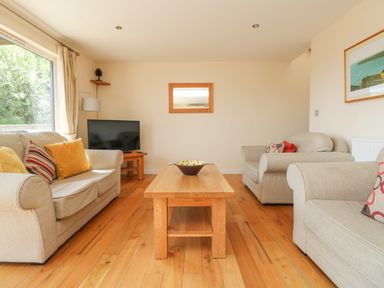 A living room with beige sofas wooden coffee table and a TV at The Willows in Winnard's Perch near St Columb Major
