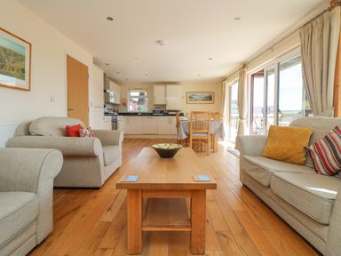 A living room with sofas and a wooden coffee table next to a kitchen and dining area at The Willows Winnard's Perch near St Columb Major