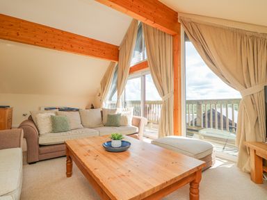 A living room with sofas a wooden coffee table and large windows at The Willows in Winnard's Perch near St Columb Major