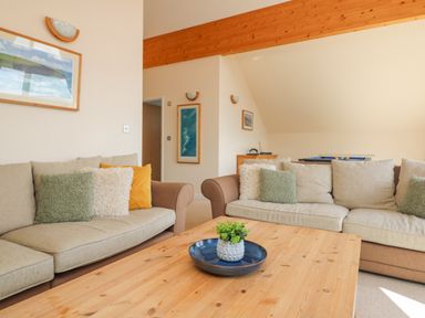 A living room with two beige sofas and a wooden coffee table with a plant on it at The Willows in Winnard's Perch near St Columb Major