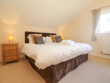 A bedroom with a double bed with pillows bedside tables with lamps and a window at The Willows Winnard's Perch near St Columb Major