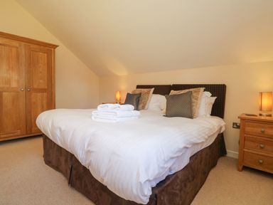 A bedroom with a double bed and folded towels on the bed at The Willows Winnard's Perch near St Columb Major