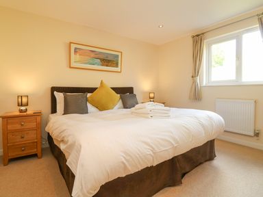 A bedroom with a double bed with pillows and folded towels bedside tables with lamps and a window at The Willows in Winnard's Perch near St Columb Major