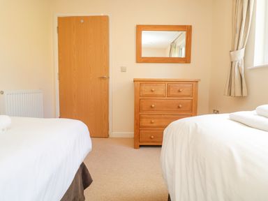 A bedroom with two beds a wooden dresser with a mirror and a wooden door at The Willows in Winnard's Perch near St Columb Major