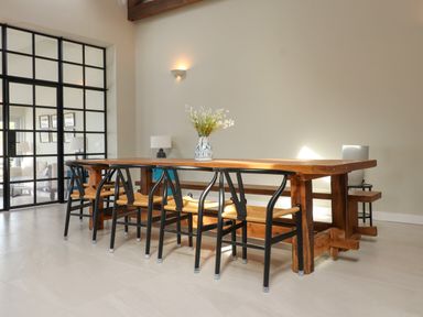 A dining room with a wooden table and black chairs with light brown seats at Beudy Mawr in Cwmystradllyn near Tremadog