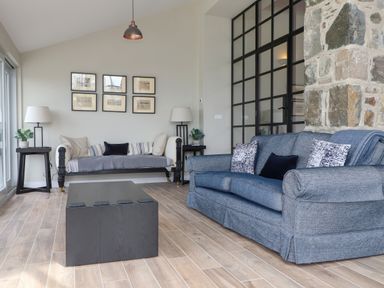 A living room with two sofas a black coffee table lamps and framed pictures on a wall at Beudy Mawr in Cwmystradllyn near Tremadog