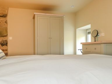 A bedroom with a bed a wardrobe and a dresser with a mirror at Beudy Mawr in Cwmystradllyn near Tremadog