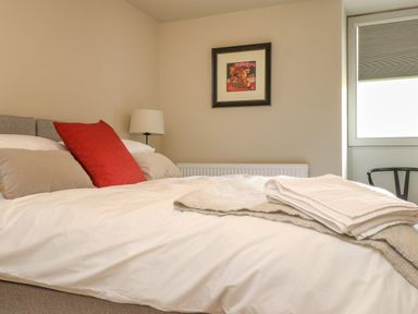 A bedroom with a bed with pillows and folded towels a table lamp and framed picture at Beudy Mawr in Cwmystradllyn near Tremadog
