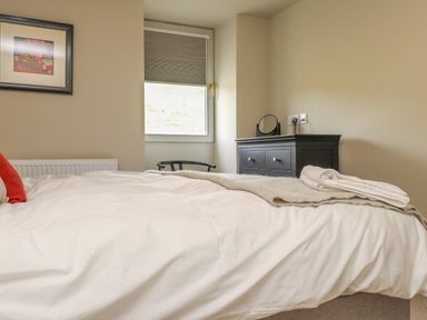 A bedroom with a bed a window a black dresser and framed wall art at Beudy Mawr in Cwmystradllyn near Tremadog