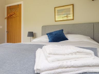 A bedroom with a bed and folded white towels on a blanket at Beudy Mawr in Cwmystradllyn near Tremadog
