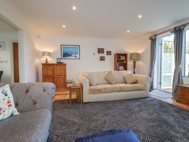 A living room with sofas cushions wooden furniture and a large window at Surf Break in Polzeath