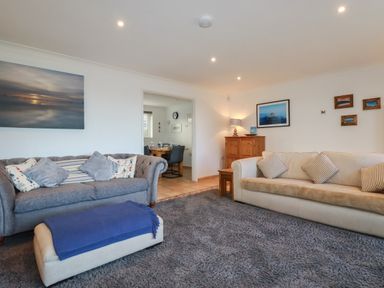 A living room with two sofas a footstool and pictures on the walls at Surf Break in Polzeath