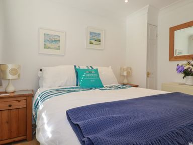 A bedroom with a double bed bedside tables lamps wall art and a mirror at Surf Break in Polzeath