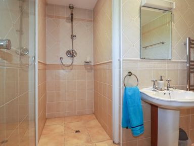 A bathroom with a walk-in shower sink mirror and blue towel at Surf Break in Polzeath