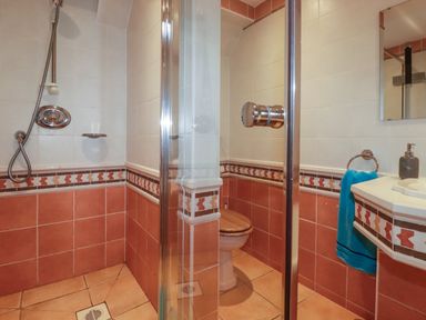 A bathroom with a shower, toilet, sink, mirror, and a blue towel at Surf Break in Polzeath