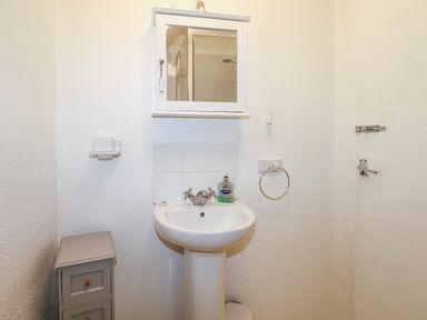 A bathroom with a pedestal sink mirror cabinet soap dispenser and small storage unit at Chalet 58 - The Beach House Kingsdown