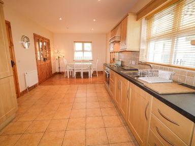 A kitchen and dining area with wooden cabinets a sink and dining table at 46 Dunalinn in Culdaff County Donegal