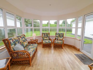 A sunroom with wicker furniture and patterned cushions at 46 Dunalinn in Culdaff County Donegal