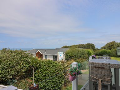 An outdoor area with table and chairs overlooking the ocean at Coogee View in Maenygroes near New Quay