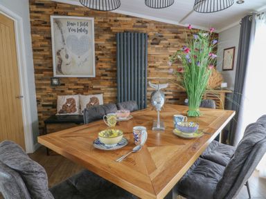 A dining room with a wooden table and chairs at Coogee View in Maenygroes near New Quay