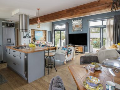 A kitchen and living area with bar stools and a television at Coogee View Maenygroes near New Quay